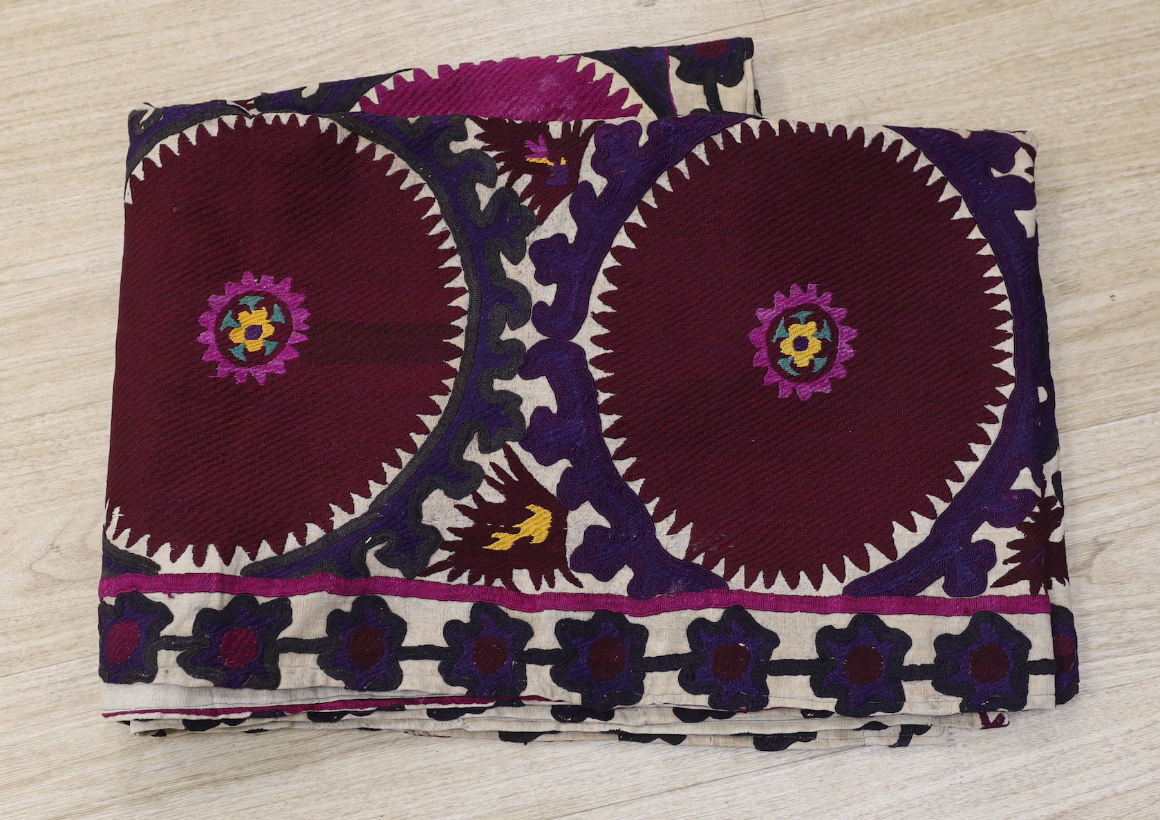 A Suzani hanging, embroidered with two rows of aubergine roundels, 255 x 90cm